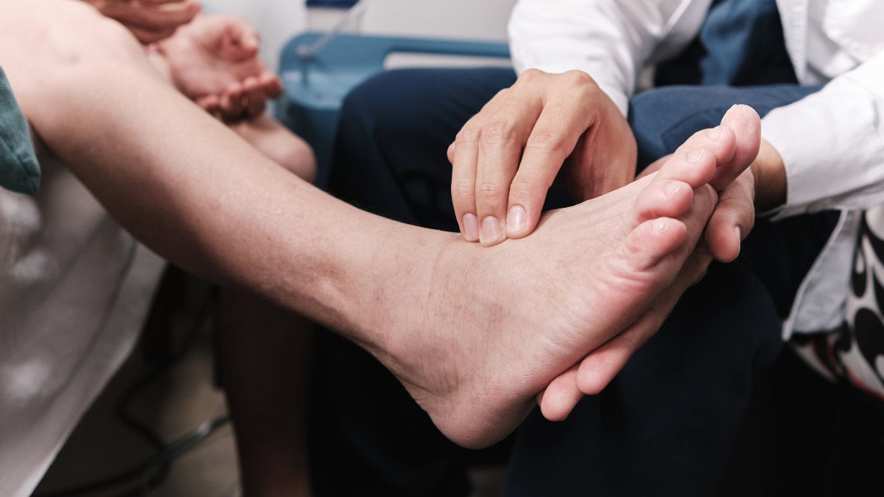 Podiatrist's hands examining the top of a patient's bare foot
